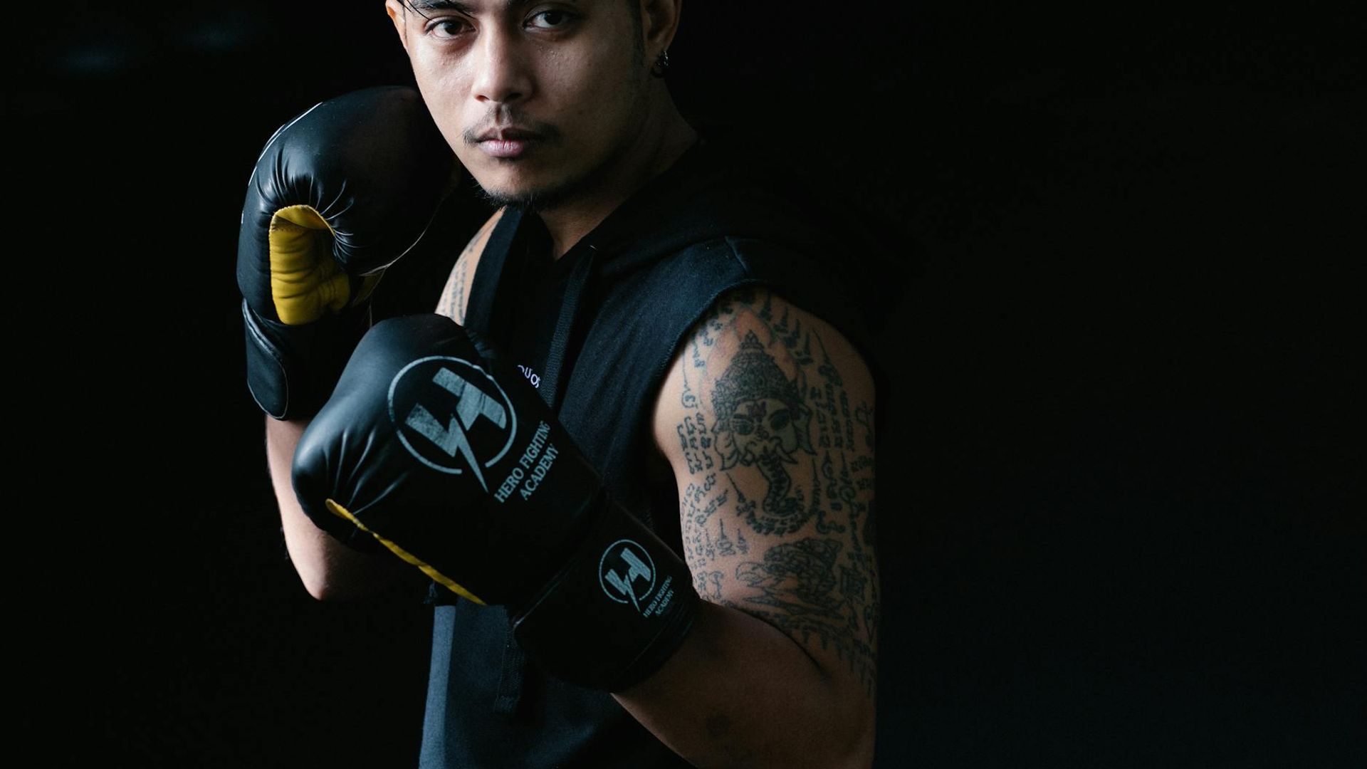 Man in a focused athletic stance in a dark, minimalist setting.